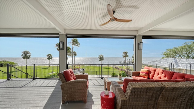 sunroom with beamed ceiling, a water view, and ceiling fan