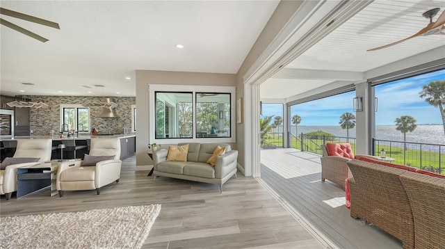 sunroom / solarium featuring plenty of natural light, ceiling fan, and a water view