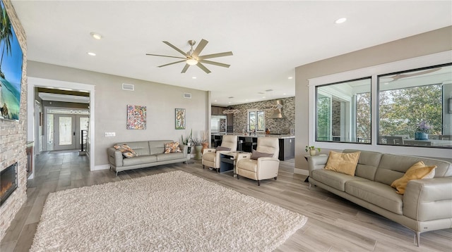 living room with a fireplace, light hardwood / wood-style flooring, and ceiling fan