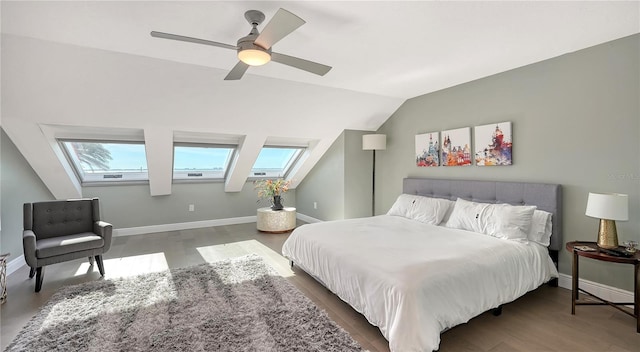 bedroom with ceiling fan, lofted ceiling with skylight, dark wood-type flooring, and multiple windows