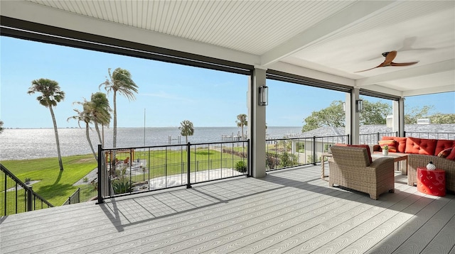 deck featuring ceiling fan, a water view, and a yard