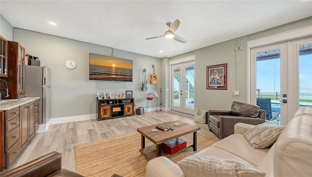 living area with baseboards, a ceiling fan, french doors, light wood-style floors, and recessed lighting