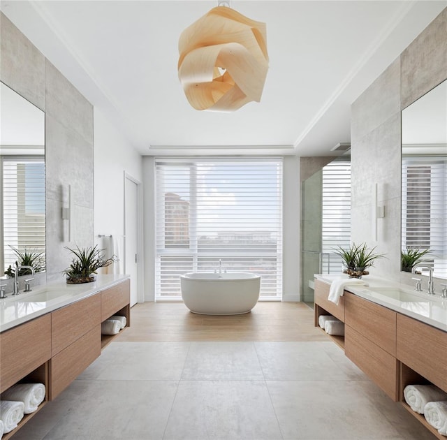 509 Golden Gate Pt Unit 3, Sarasota, FL 34236 - bathroom featuring two vanities, a freestanding tub, a shower stall, tile patterned flooring, and floor to ceiling windows