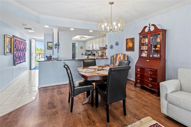 dining room featuring light wood-type flooring, ornamental molding, and an inviting chandelier