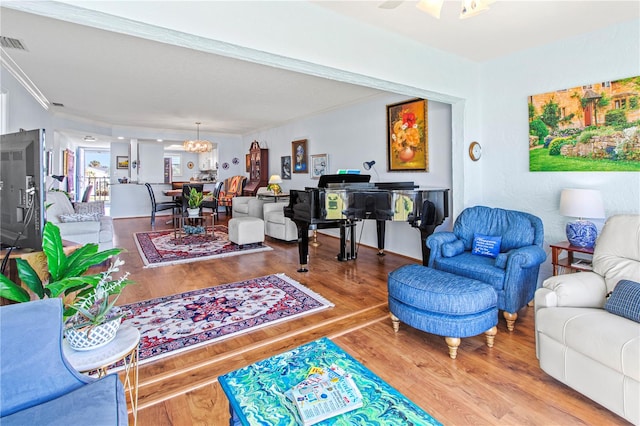 living room featuring crown molding, ceiling fan with notable chandelier, and hardwood / wood-style flooring