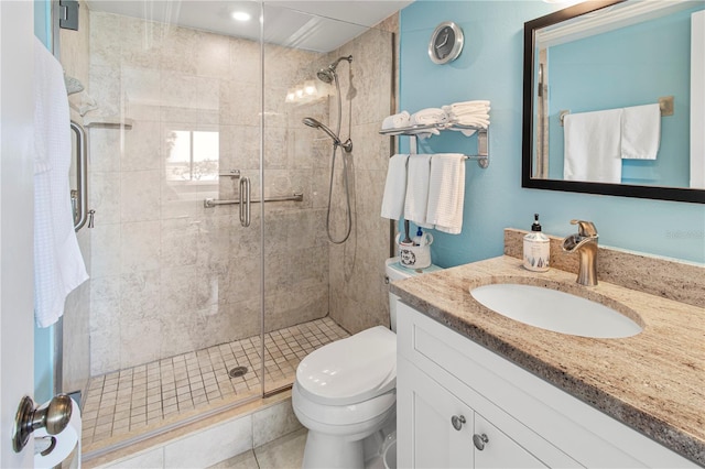 bathroom with tile patterned floors, vanity, a shower with shower door, and toilet