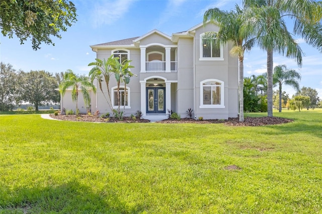 view of front of house with a balcony, a front yard, and french doors