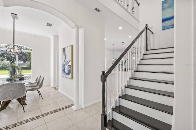 tiled foyer featuring crown molding and a notable chandelier