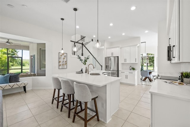 kitchen featuring white cabinetry, sink, ceiling fan, stainless steel fridge, and pendant lighting