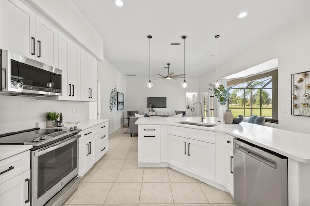 kitchen featuring sink, white cabinets, hanging light fixtures, and appliances with stainless steel finishes