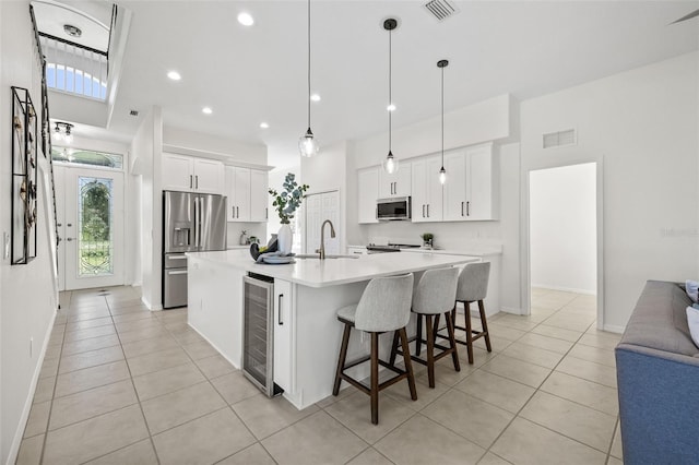 kitchen with white cabinets, pendant lighting, a center island with sink, and appliances with stainless steel finishes