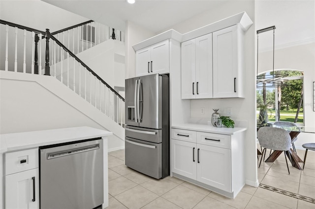 kitchen with white cabinetry, appliances with stainless steel finishes, pendant lighting, light tile patterned floors, and ornamental molding