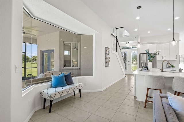 interior space featuring french doors, ceiling fan, sink, white cabinets, and hanging light fixtures