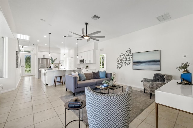 living room featuring ceiling fan, sink, and light tile patterned floors