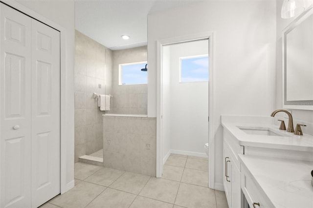 bathroom featuring tile patterned floors, vanity, a tile shower, and toilet