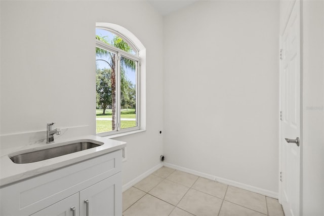 washroom with hookup for an electric dryer, a healthy amount of sunlight, light tile patterned flooring, and sink