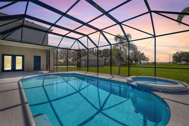 pool at dusk featuring an in ground hot tub, french doors, glass enclosure, a patio, and a lawn