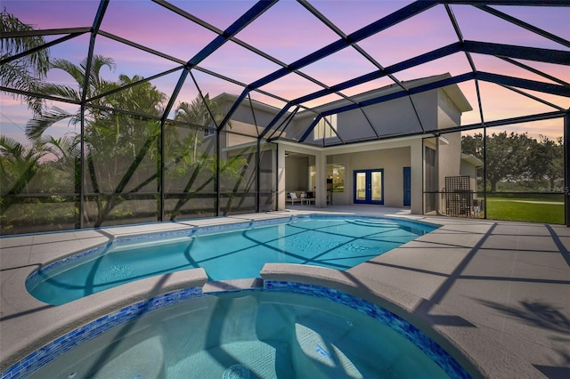 pool at dusk featuring glass enclosure, an in ground hot tub, french doors, and a patio area