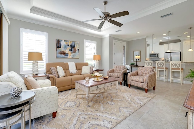 living room with a raised ceiling, ceiling fan, and crown molding