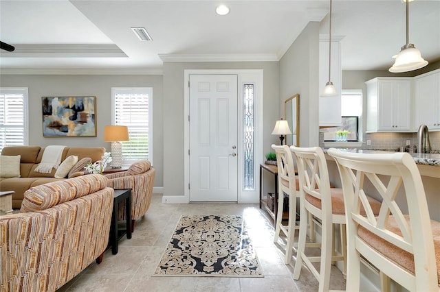 foyer entrance with a healthy amount of sunlight, ornamental molding, sink, and light tile patterned floors