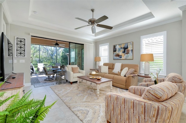 living room featuring light tile patterned floors, a tray ceiling, ceiling fan, and crown molding