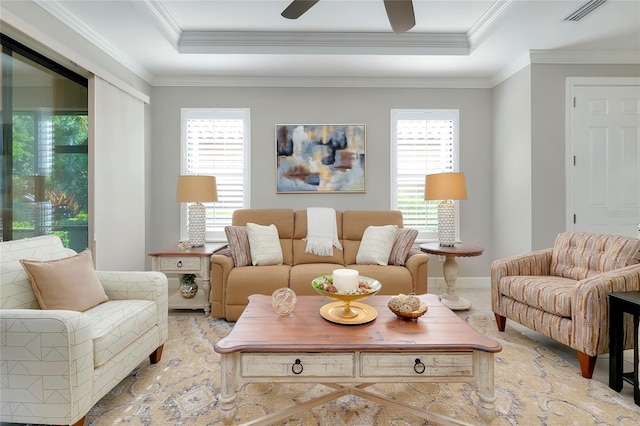 living room with a raised ceiling, a wealth of natural light, crown molding, and ceiling fan