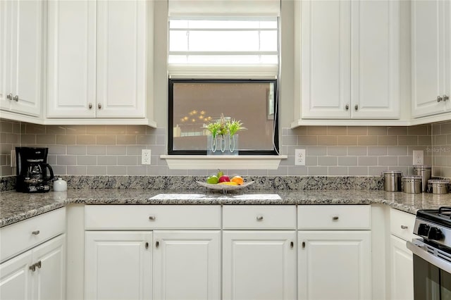 kitchen featuring light stone counters, white cabinetry, and backsplash