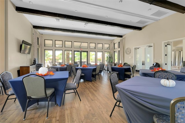 dining area with beam ceiling, light wood-type flooring, and french doors