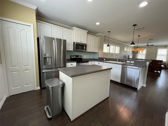 kitchen featuring sink, kitchen peninsula, decorative light fixtures, a kitchen island, and appliances with stainless steel finishes