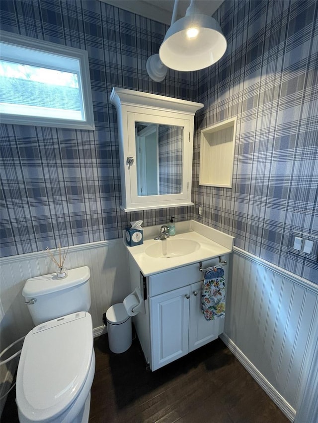 bathroom with wooden walls, hardwood / wood-style floors, vanity, and toilet