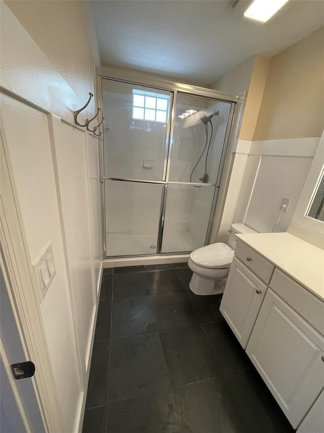 bathroom with vanity, toilet, and a shower with door