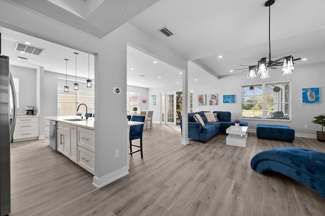 kitchen with white cabinets, appliances with stainless steel finishes, light wood-type flooring, and hanging light fixtures