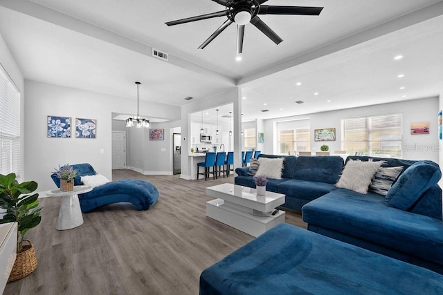 living room with hardwood / wood-style floors and ceiling fan with notable chandelier