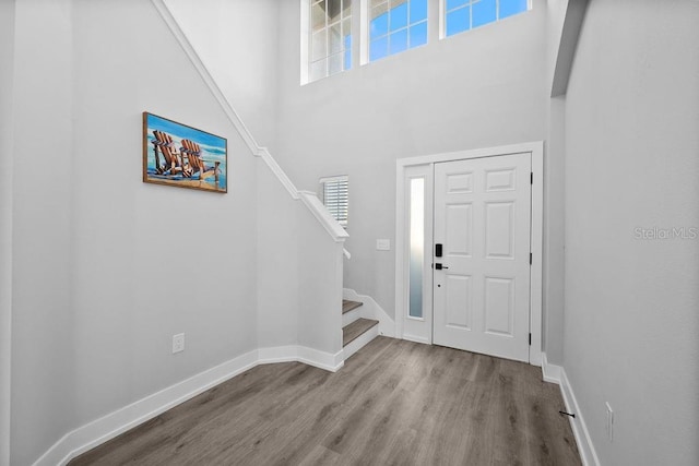 foyer entrance with light wood-type flooring and a towering ceiling