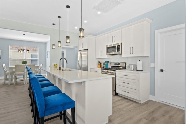 kitchen featuring a center island with sink, white cabinets, stainless steel appliances, and sink