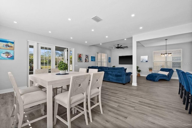 dining area featuring ceiling fan with notable chandelier and light wood-type flooring