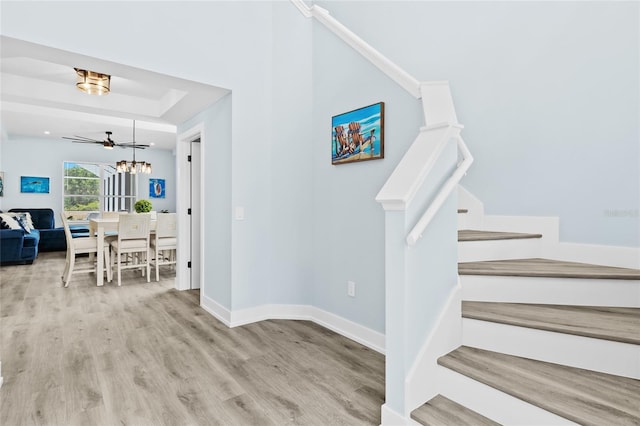 stairway featuring ceiling fan, a raised ceiling, and wood-type flooring