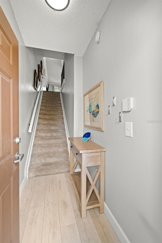 hall featuring light hardwood / wood-style floors and a textured ceiling