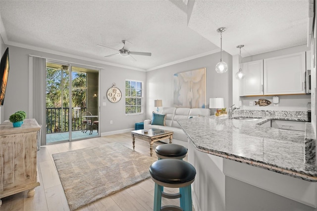 kitchen featuring light stone countertops, sink, ceiling fan, a textured ceiling, and white cabinets