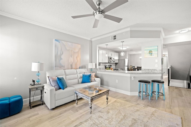 living area with a textured ceiling, ornamental molding, visible vents, and light wood-style floors