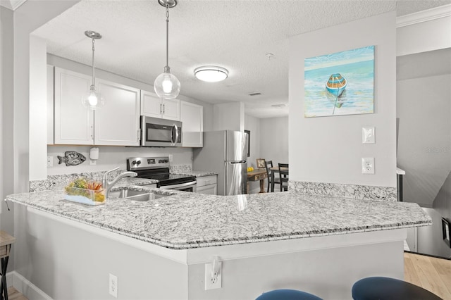 kitchen with stainless steel appliances, light stone counters, and a peninsula