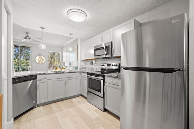 kitchen featuring appliances with stainless steel finishes, light wood-style floors, a sink, and light stone counters