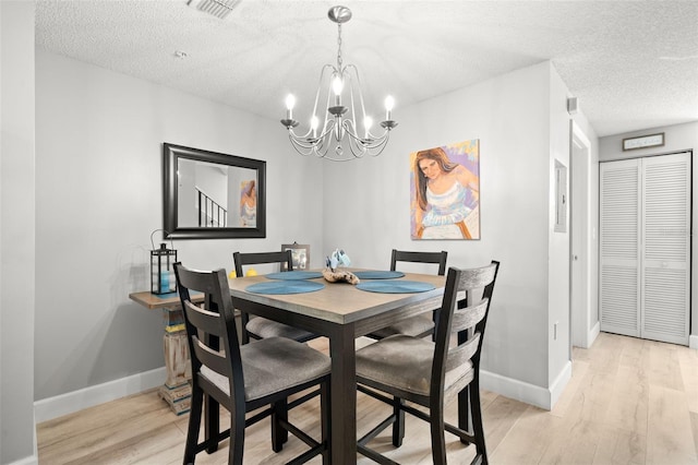 dining room featuring light wood-type flooring, visible vents, a textured ceiling, and baseboards