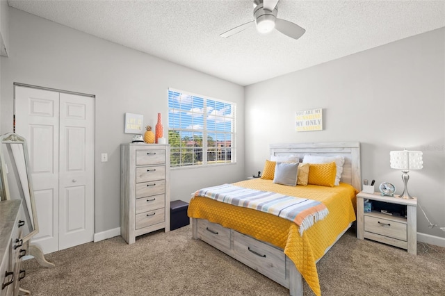 bedroom with a closet, light colored carpet, a ceiling fan, a textured ceiling, and baseboards