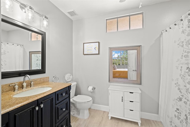 bathroom featuring visible vents, toilet, vanity, wood finished floors, and baseboards