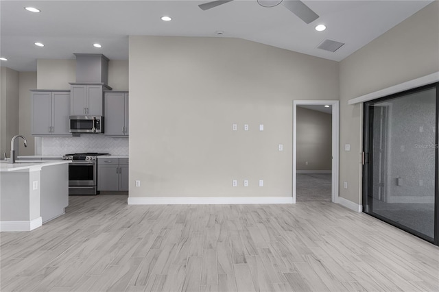 unfurnished living room with ceiling fan, sink, high vaulted ceiling, and light wood-type flooring