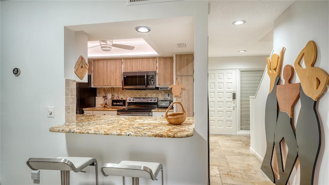 kitchen with backsplash, light stone countertops, ceiling fan, and stainless steel appliances