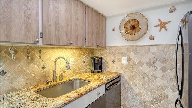 kitchen featuring sink, light stone counters, decorative backsplash, light brown cabinetry, and appliances with stainless steel finishes