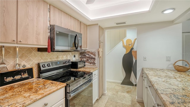 kitchen featuring decorative backsplash, light brown cabinetry, light stone counters, and appliances with stainless steel finishes