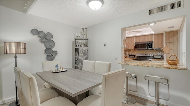 dining area featuring a textured ceiling and light hardwood / wood-style flooring